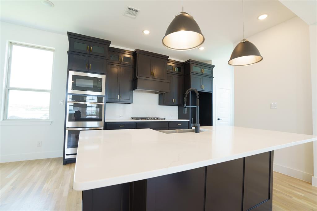 9311 Easy Street Rowlett, TX 75088 - Photo 4 of 22 Kitchen with decorative light fixtures, glass insert cabinets, stainless steel appliances, a center island with sink, and recessed lighting
