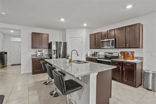 a kitchen with kitchen island granite countertop stainless steel appliances and wooden cabinets