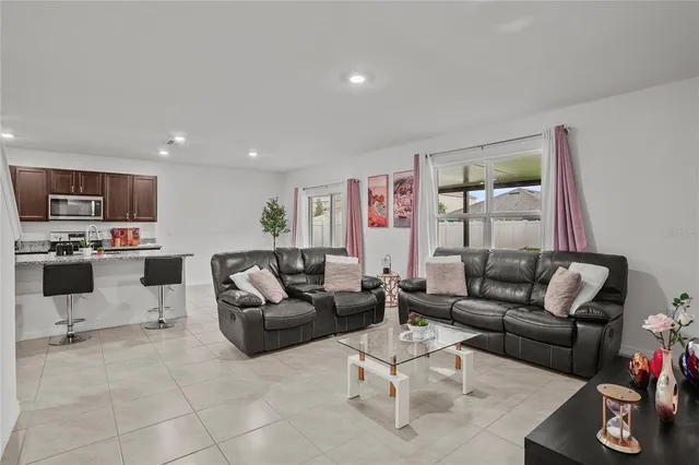 a living room with furniture kitchen view and a window