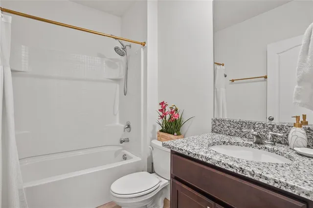 a bathroom with a granite countertop sink a toilet and shower