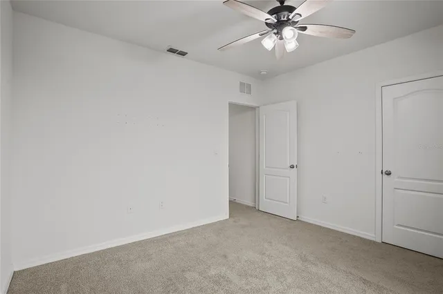 a view of an empty room and chandelier fan