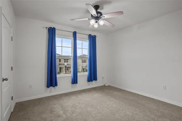 an empty room with windows and ceiling fan