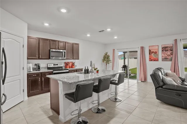 a kitchen with stainless steel appliances granite countertop a stove top oven a sink dishwasher a dining table and chairs with wooden floor