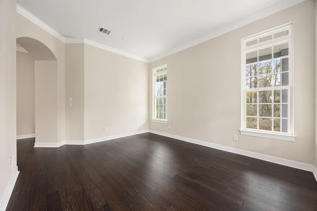an empty room with wooden floor and windows