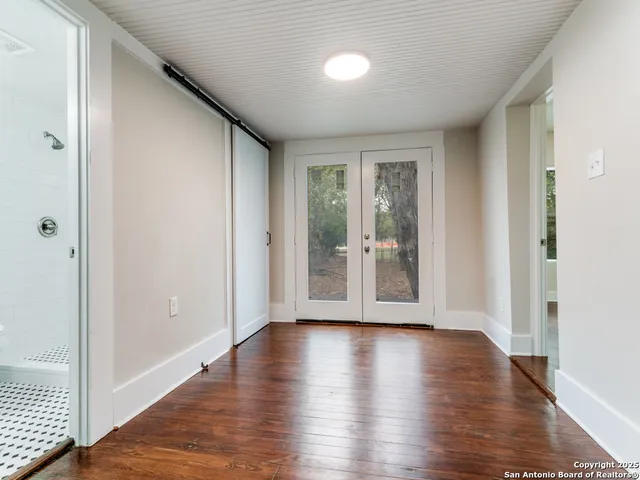a view of an empty room with wooden floor and a window