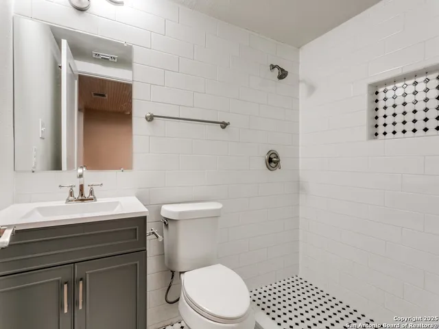 a bathroom with a sink a toilet a mirror and shower