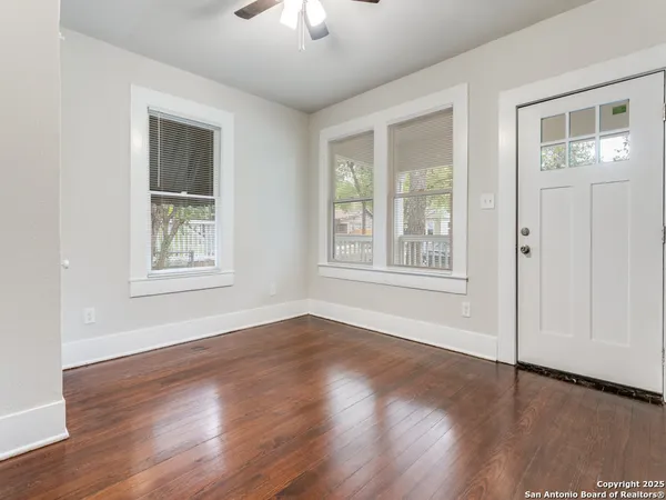 a view of an empty room with wooden floor and a window