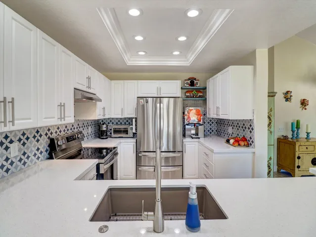 a kitchen with stainless steel appliances kitchen island granite countertop a refrigerator and a sink