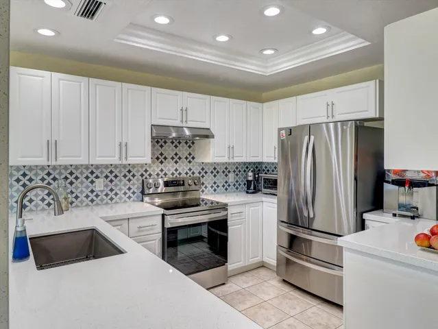 a kitchen with stainless steel appliances a refrigerator sink and white cabinets