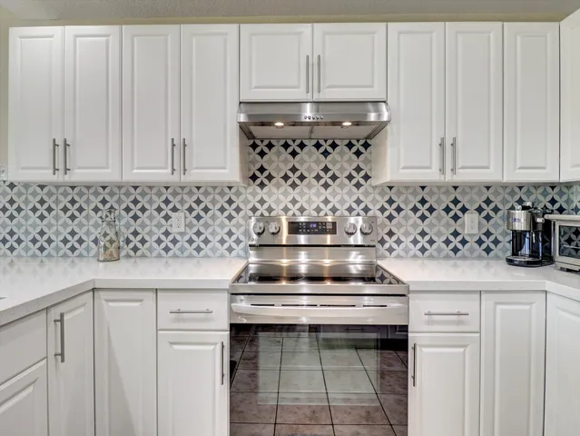 a kitchen with a stove and white cabinets
