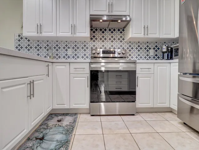 a kitchen with granite countertop white cabinets and stainless steel appliances