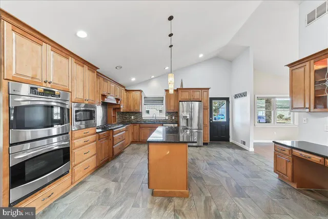 a kitchen with stainless steel appliances granite countertop a refrigerator a stove and a wooden floors