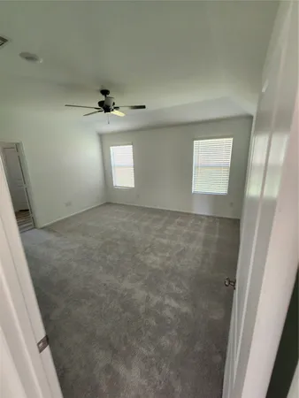 an empty room with windows and ceiling fan