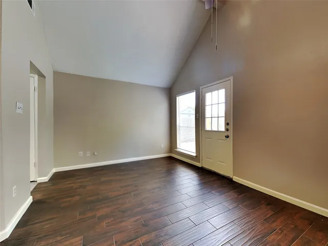 a view of an empty room with wooden floor and window