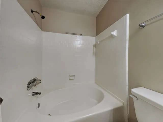 a white bath tub sitting next to a white toilet and a shower
