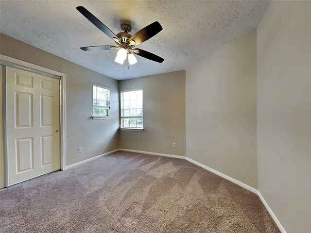 an empty room with windows and fan