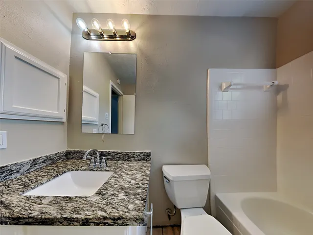 a bathroom with a granite countertop sink mirror vanity and toilet