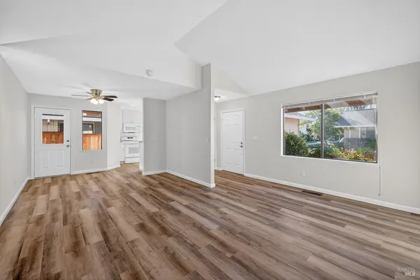 a view of empty room with wooden floor and fan