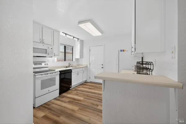 a kitchen with kitchen island white cabinets and white appliances