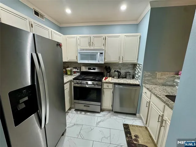 a kitchen with stainless steel appliances granite countertop a refrigerator sink and stove