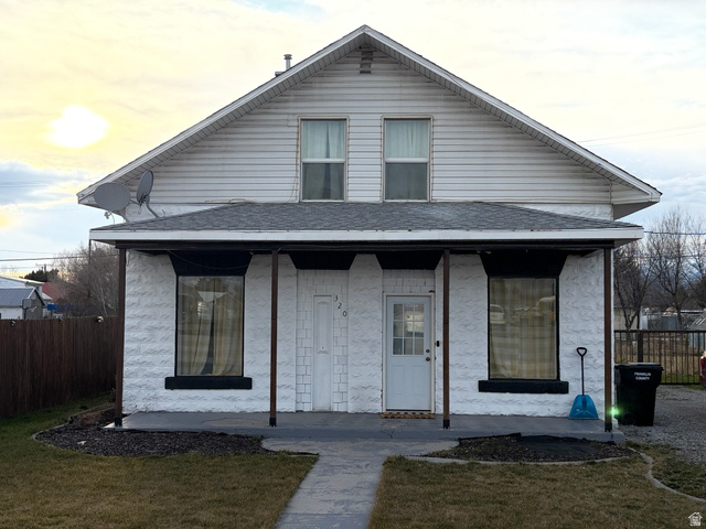 View of front of house with covered porch and a shingled roof