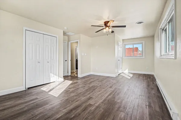 an empty room with wooden floor chandelier fan and windows
