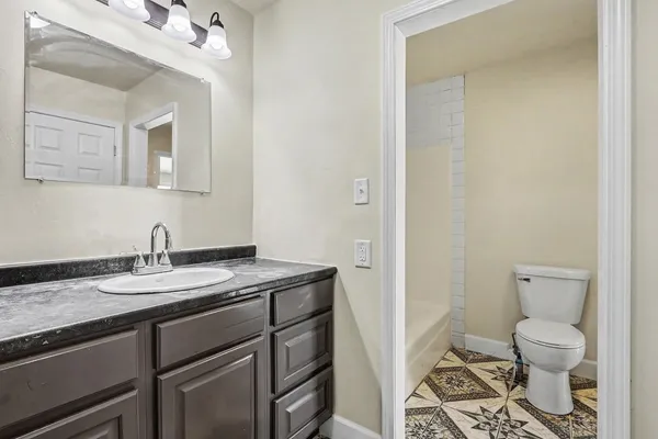 a bathroom with a granite countertop sink a toilet and a mirror