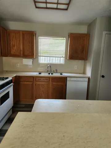 a kitchen with stainless steel appliances a sink a stove a refrigerator a window and cabinets