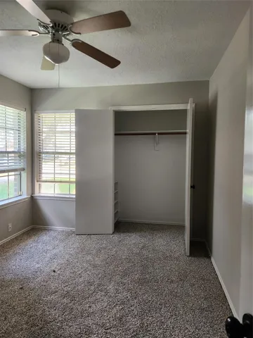 an empty room with windows and fan