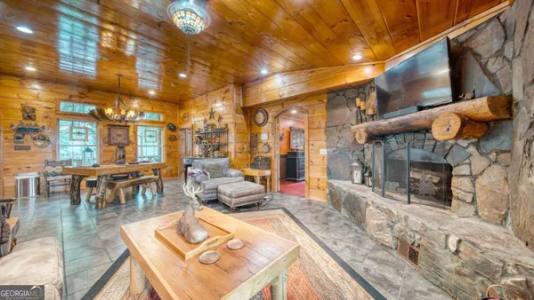 a living room with fireplace furniture and a dining table with wooden floor
