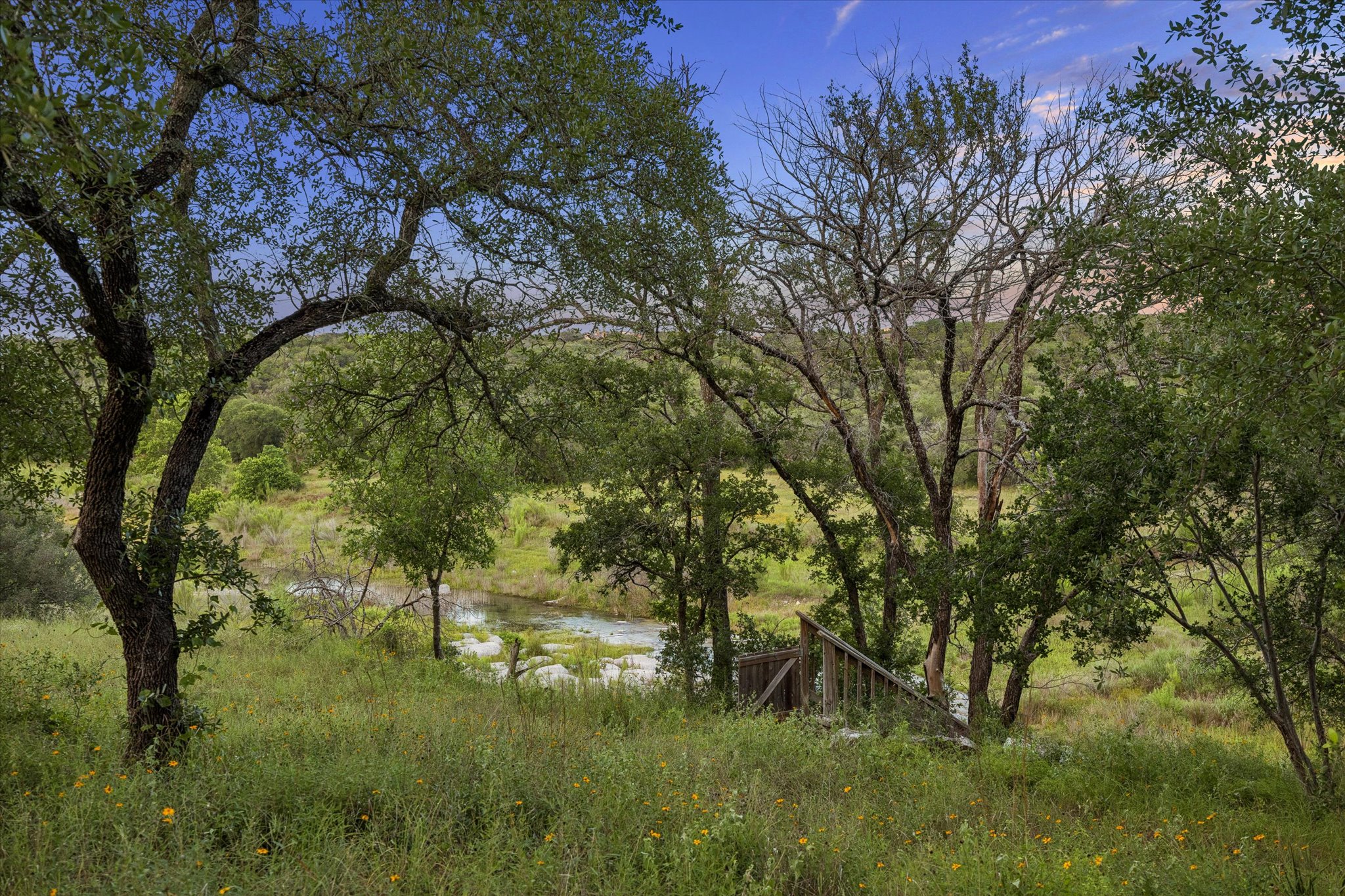 3719 Bee Creek Road Spicewood, TX 78669 - Photo 38 of 40 A tranquil water feature with a wooden staircase provides access to the verdant, rolling landscape.