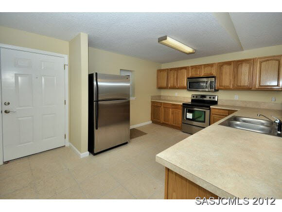 171 Blocker Street St. Augustine, FL 32084 - Photo 5 of 13 a kitchen with stainless steel appliances granite countertop a sink a stove a refrigerator a microwave with white cabinets and wooden floor