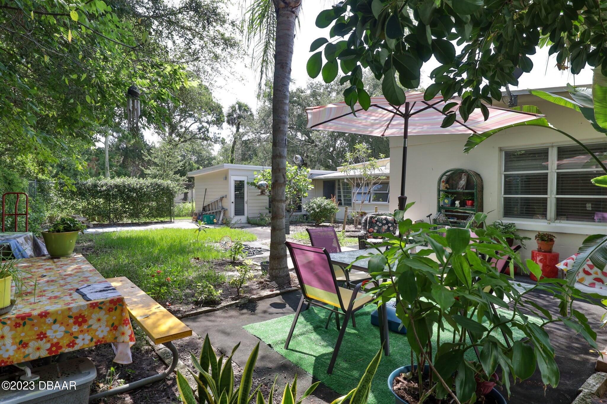 113 Evergreen Avenue Edgewater, FL 32132 - Photo 39 of 47 a view of a patio with table and chairs potted plants and large tree