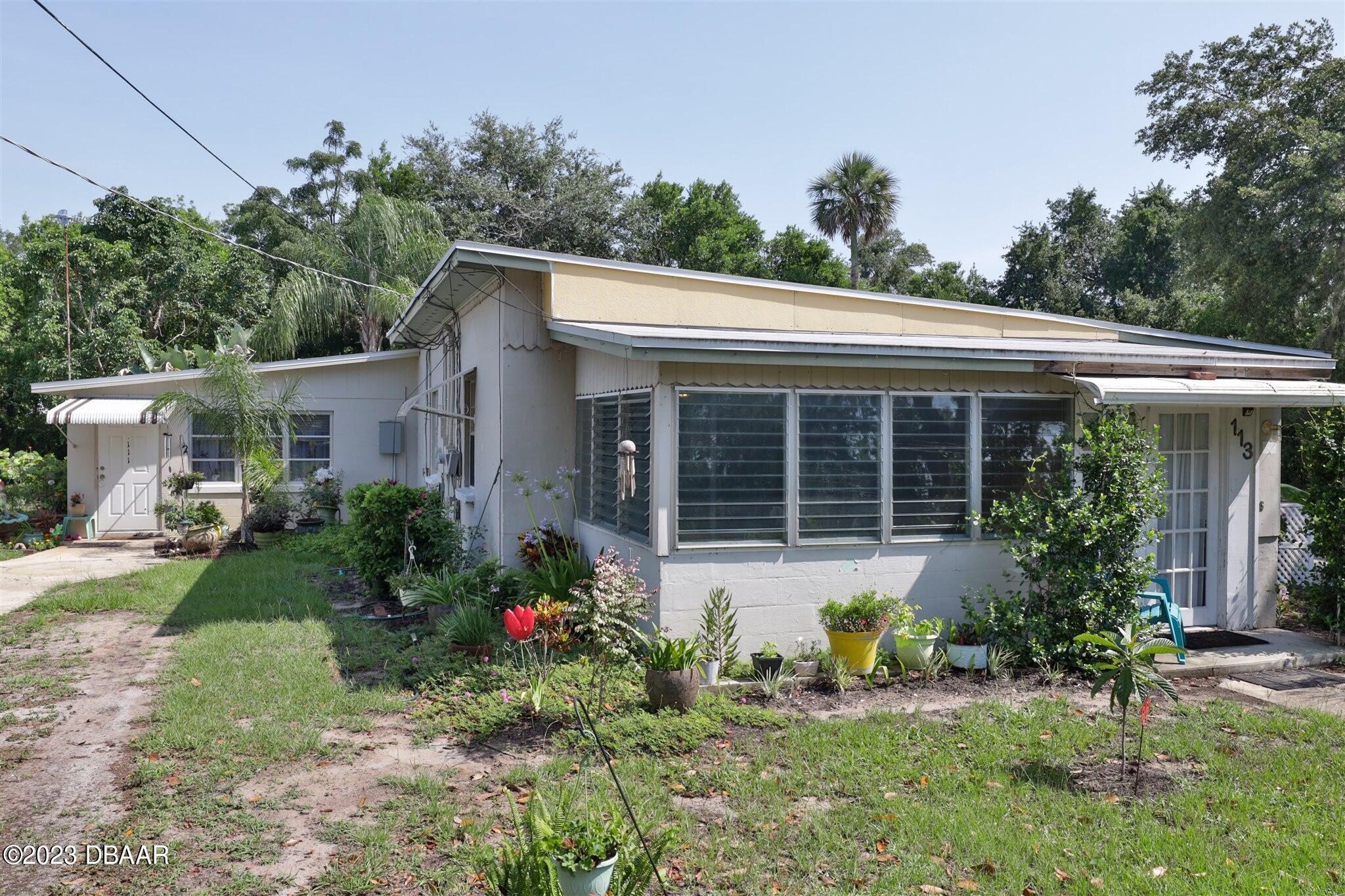113 Evergreen Avenue Edgewater, FL 32132 - Photo 4 of 47 a front view of a house with garden and porch
