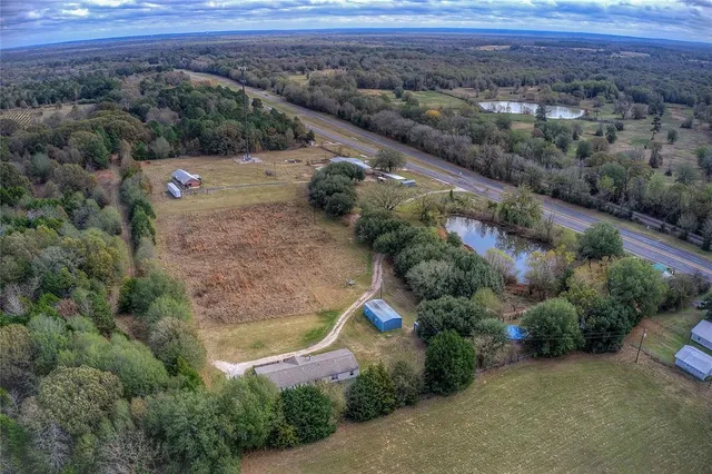 an aerial view of residential houses with outdoor space and trees