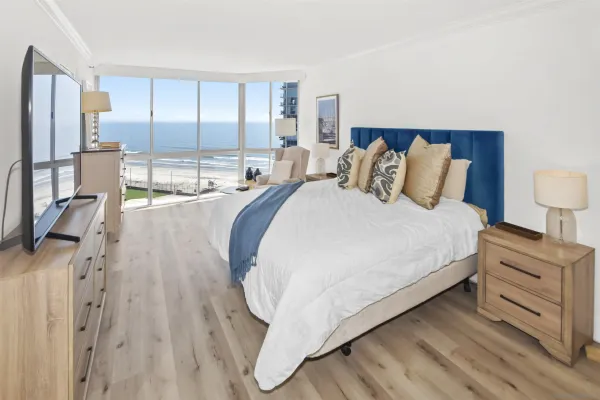 a spacious bedroom with a bed and a dresser next to a window