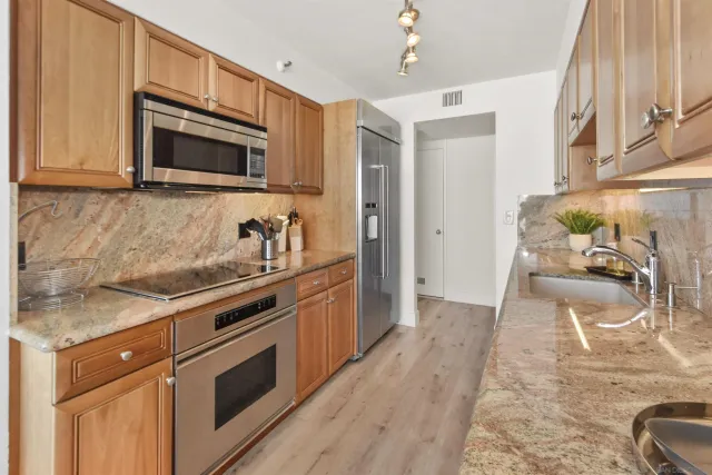 a kitchen with stainless steel appliances granite countertop a stove a sink and a microwave