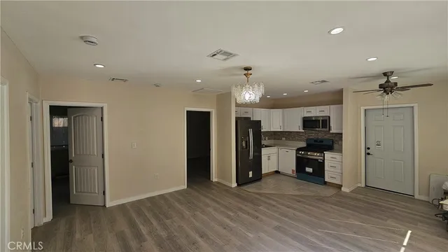 an empty room with kitchen appliances and wooden floor