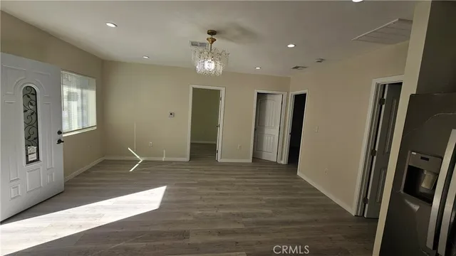 a view of a livingroom with wooden floor and a refrigerator