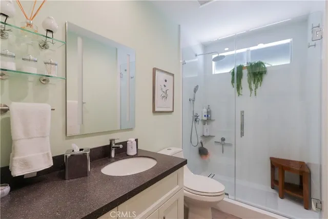 a bathroom with a granite countertop sink a toilet a mirror and shower