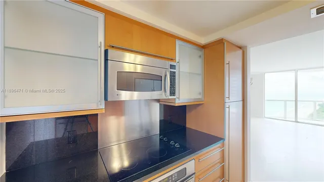 a view of kitchen with stainless steel appliances granite countertop cabinets and empty room