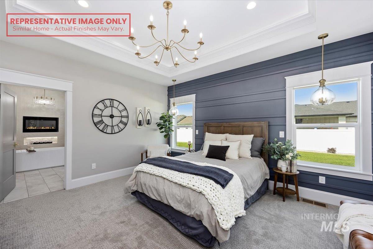 1513 Lavender Rupert, ID 83350 - Photo 4 of 16 Bedroom with hanging lights, light carpet, a glass covered fireplace, a raised ceiling, and ornamental molding