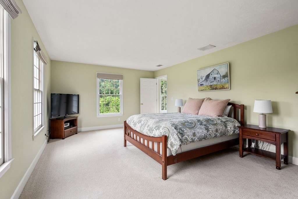 181 Maple Street Sherborn, MA 01770 - Photo 23 of 41 a spacious bedroom with a bed a couch and a flat tv screen on dresser