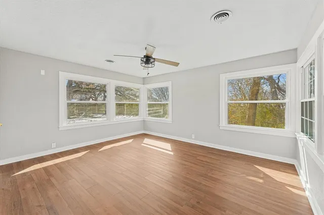a view of an empty room with a window and wooden floor