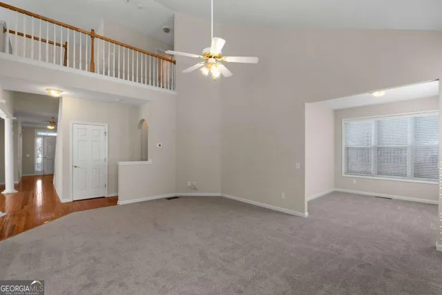 an empty room with windows and chandelier fan