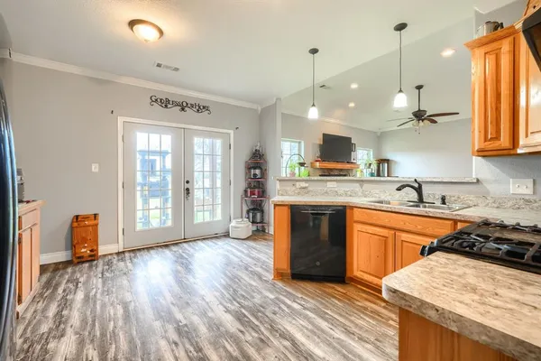 a large kitchen with stainless steel appliances granite countertop a sink dishwasher a stove and white countertops with wooden floor