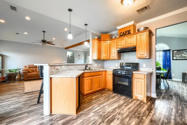 a kitchen with stainless steel appliances granite countertop a sink a stove and a wooden floors