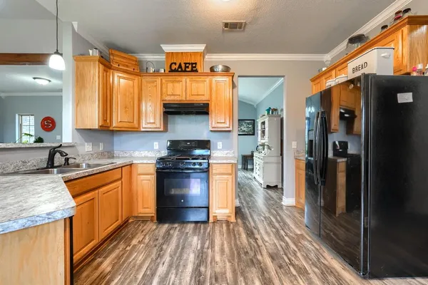 a kitchen with stainless steel appliances a refrigerator a sink and wooden cabinets
