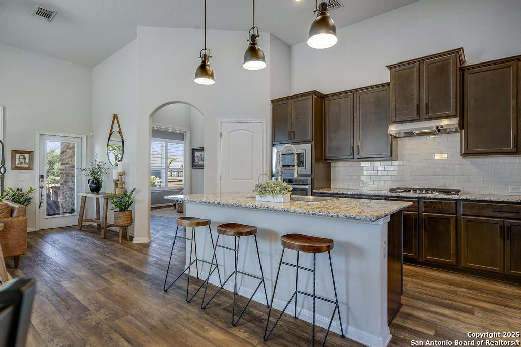 12805 Big Tank Ranch San Antonio, TX 78245 - Photo 16 of 35 a kitchen with stainless steel appliances granite countertop a stove a sink dishwasher a dining table and chairs with wooden floor