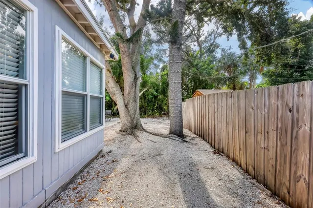 a view of a backyard with wooden fence and large trees